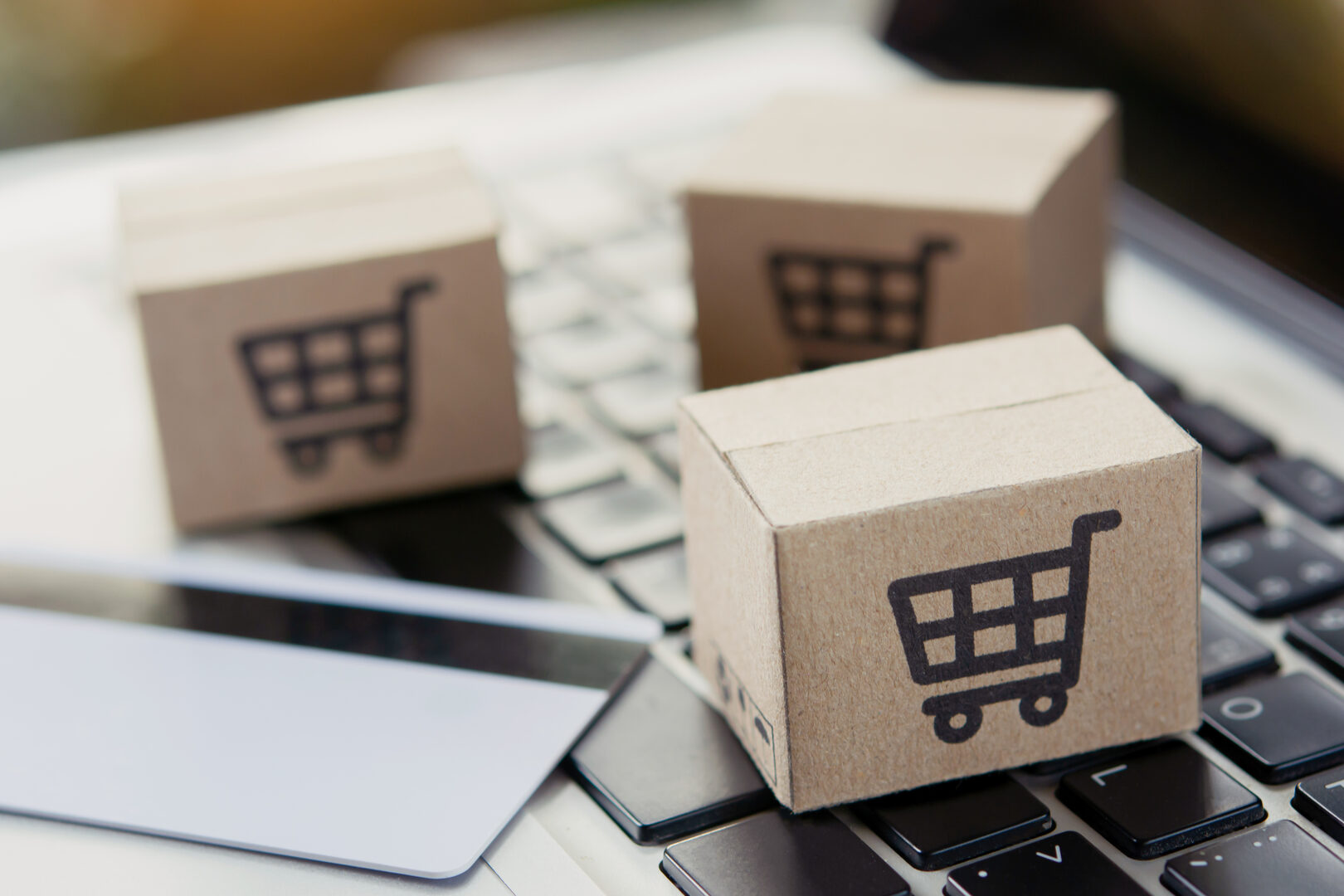Cardboard boxes with cart icons on laptop keyboard
