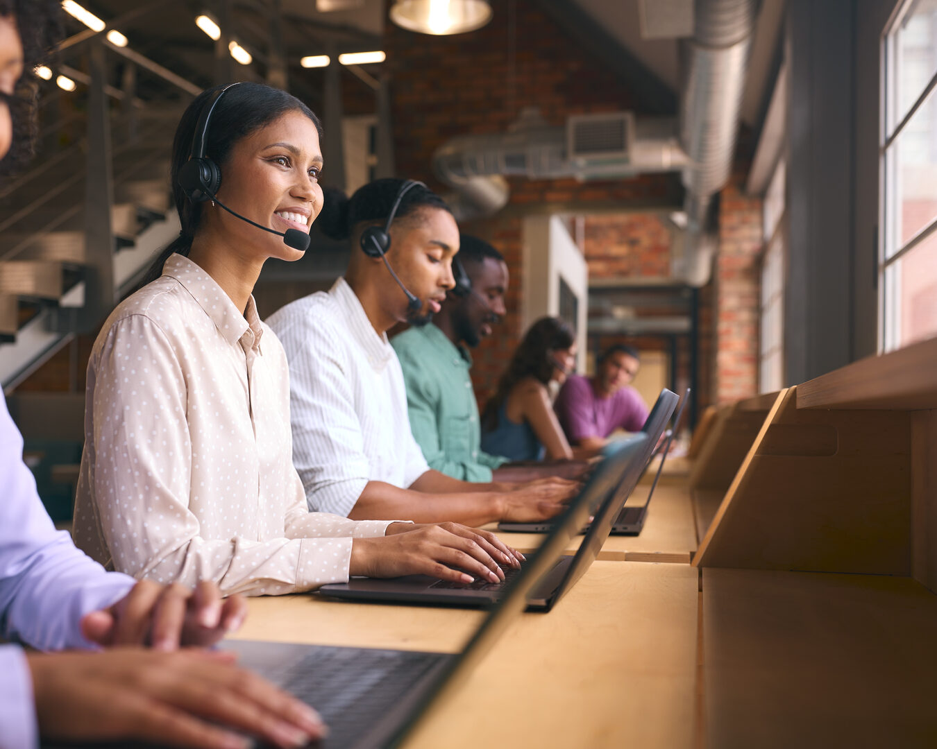 Multicultural support team at laptops in modern office