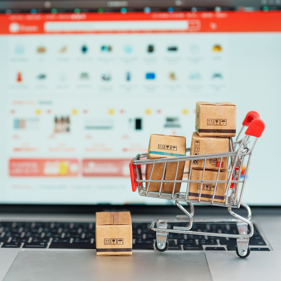 Miniature shopping cart with boxes on laptop keyboard